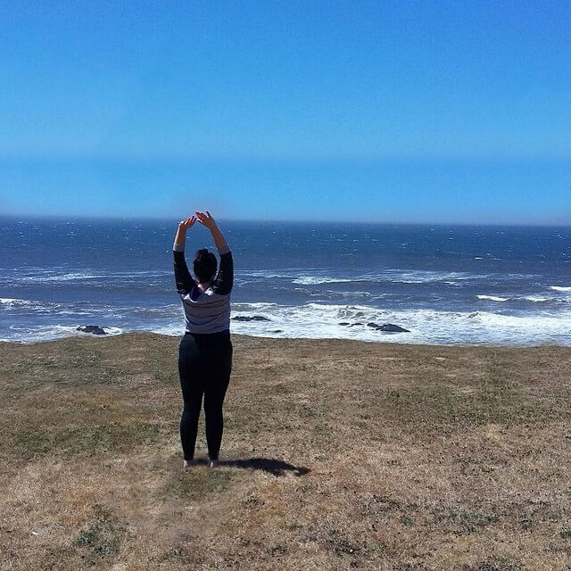 picture of Emily doing yoga at the coast